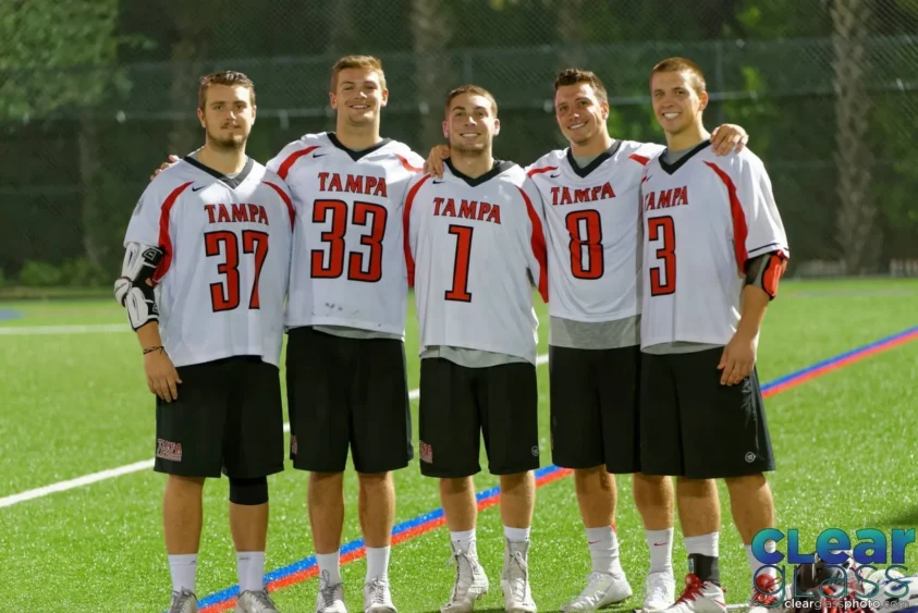 Five University of Tampa lacrosse players pose together on the field