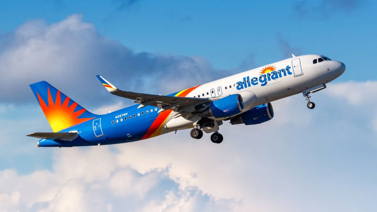 Allegiant Air passenger jet climbing through a blue sky with clouds.