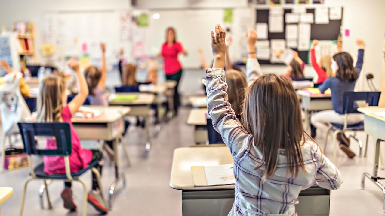 Students raise their hands during a lesson in an elementary school classroom