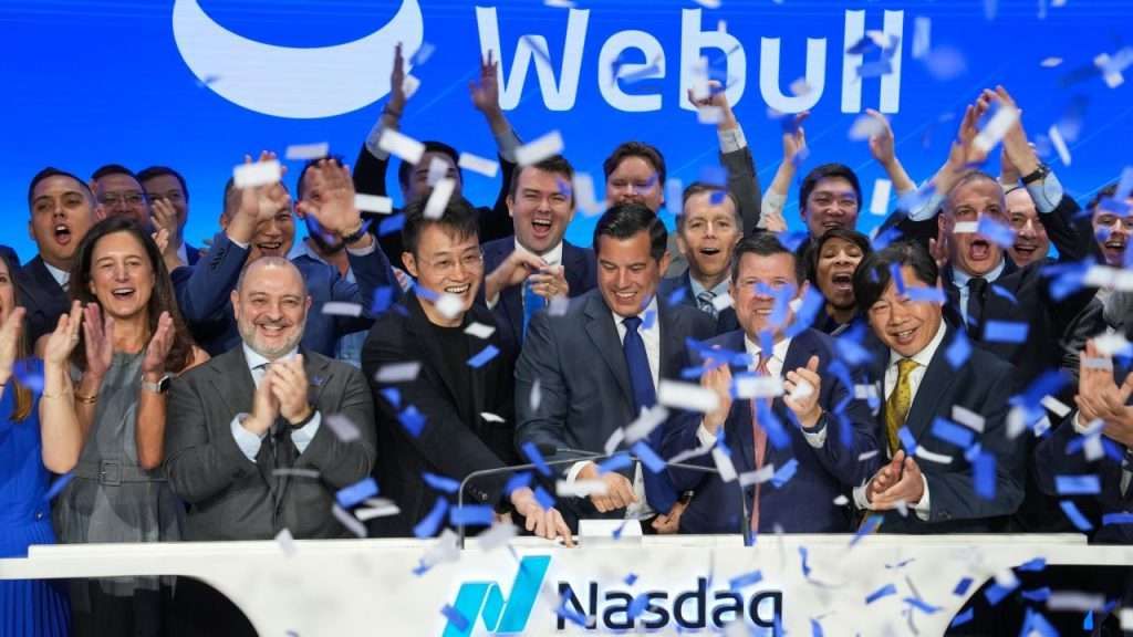 Webull executives and employees celebrate at the Nasdaq MarketSite as confetti falls.