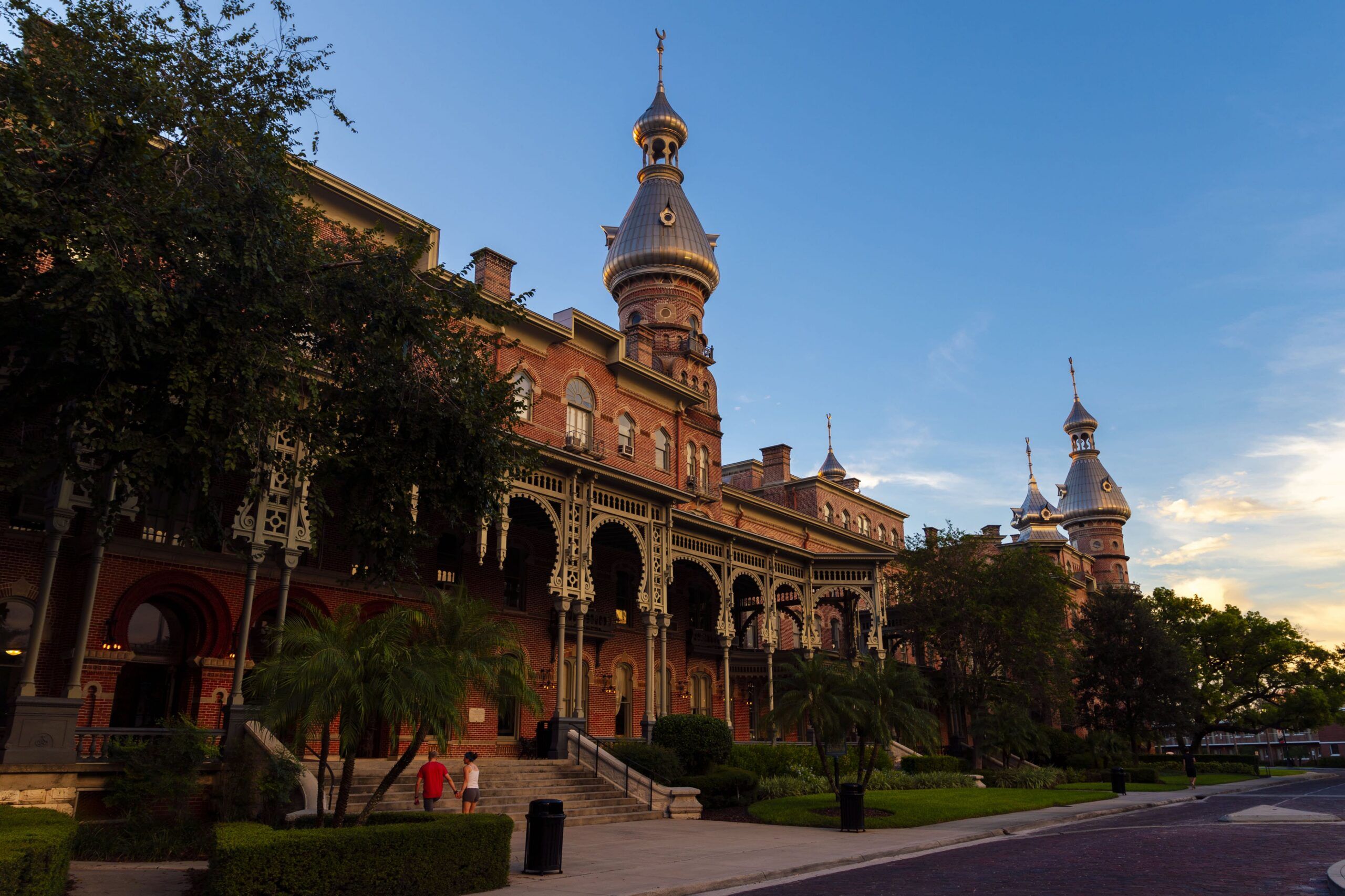 Historic Plant Hall at the University of Tampa, featuring red brick architecture, ornate verandas and distinctive silver minarets at sunset.