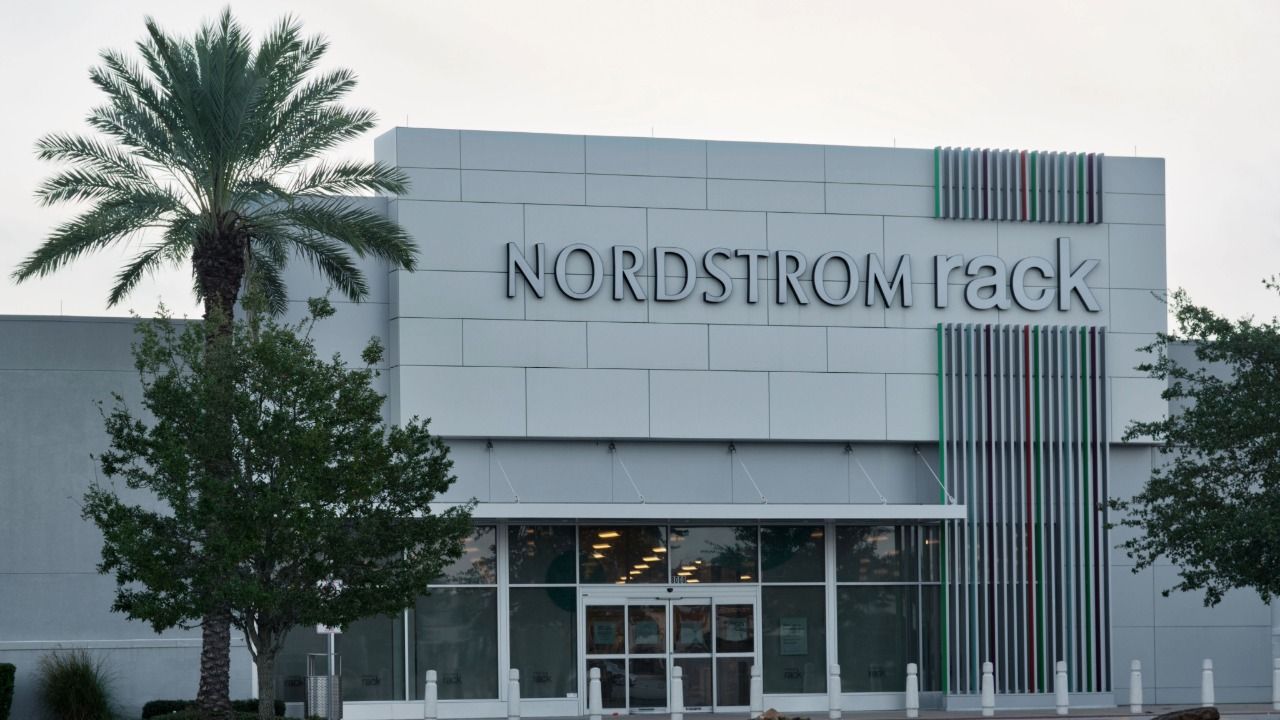 Exterior of a Nordstrom Rack store with the retailer's sign above the entrance and palm trees in front.