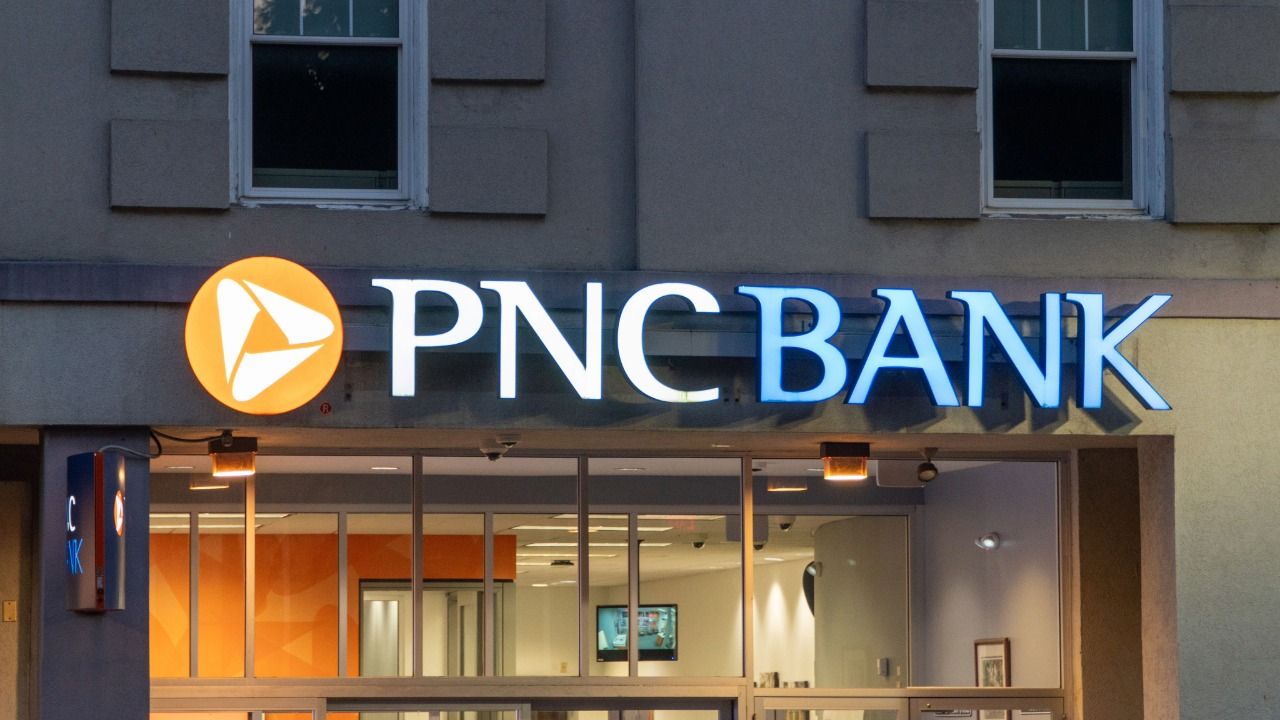 Stock photo of a PNC Bank branch entrance with illuminated signage above glass doors and windows.