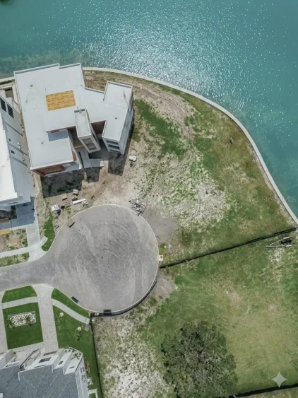 Aerial photos of Ndamukong Suh's former South Tampa waterfront lot in Madsen Isles, showing the vacant property, seawall, surrounding luxury homes and Tampa Bay.