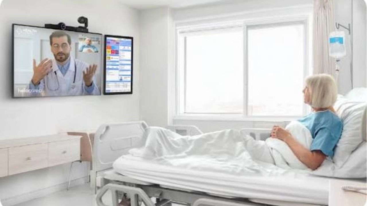 Patient in a hospital bed speaks with a doctor on a video screen using hellocare.ai virtual care technology.