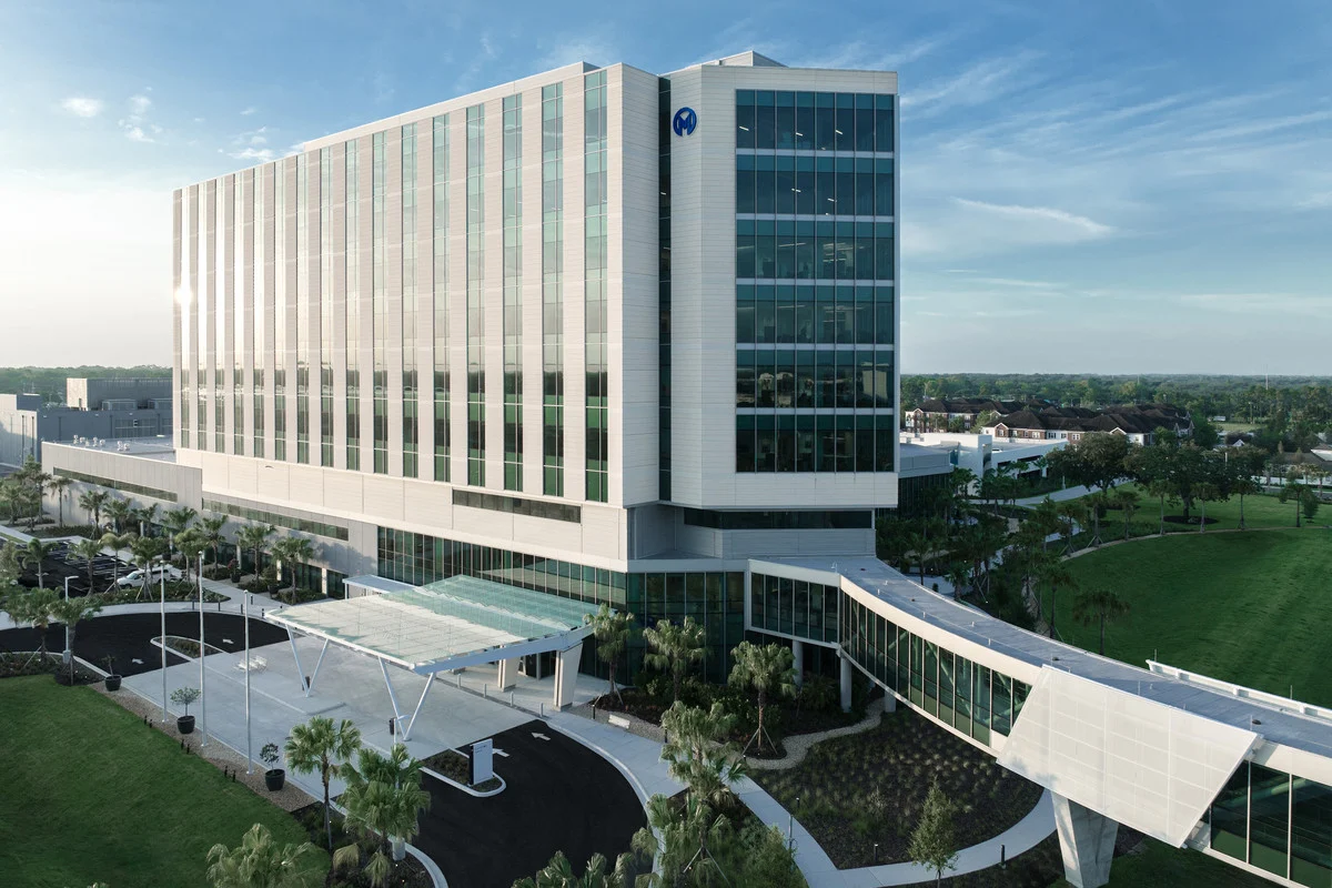 Aerial view of a multistory Moffitt Cancer Center building with glass windows and a covered entrance.